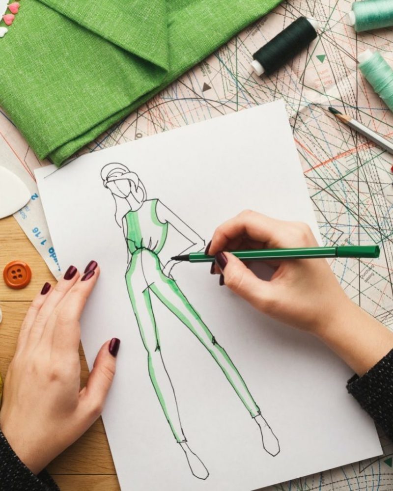 Top view on woman designer drawing clothes sketches